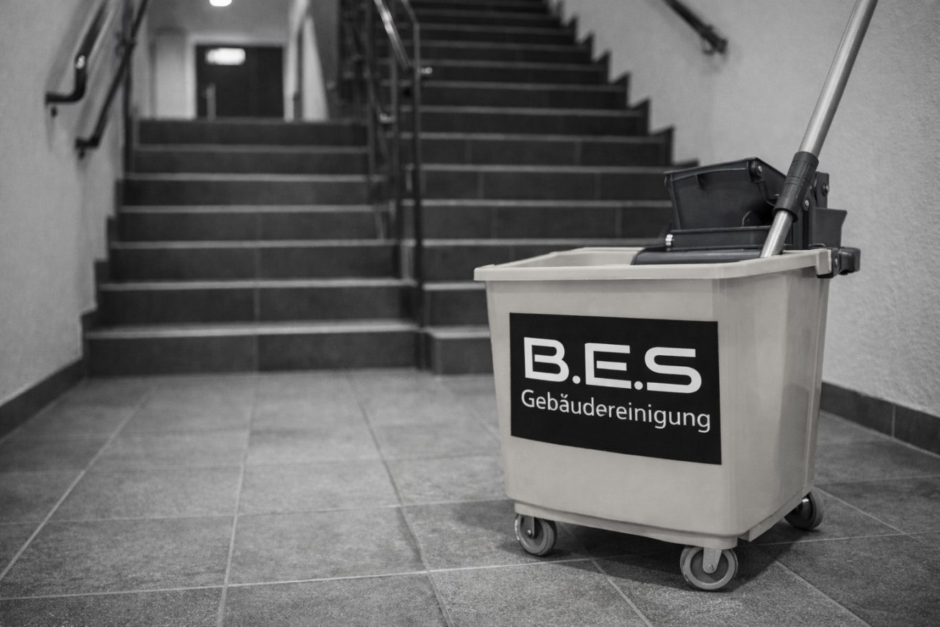 Treppenhausreinigung Reinigungswagen mit Logo steht an einer Treppe in einem Gebäude.